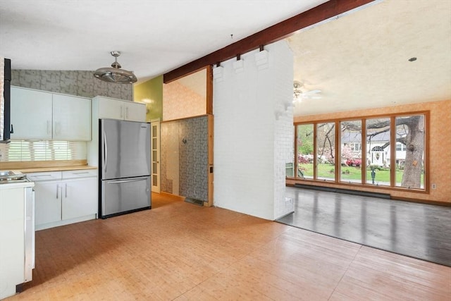 kitchen featuring freestanding refrigerator, range, ceiling fan, high vaulted ceiling, and white cabinetry