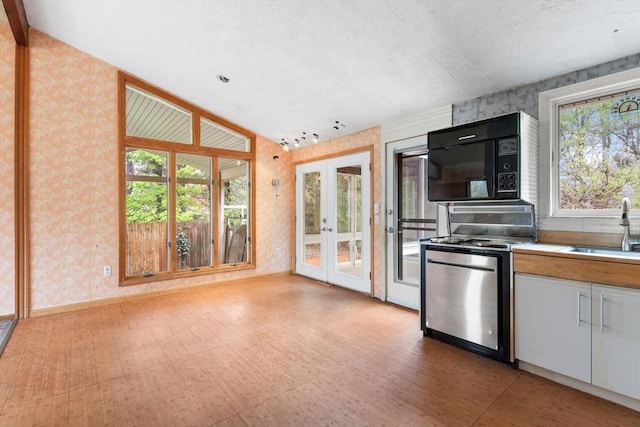 kitchen with black microwave, wallpapered walls, a sink, french doors, and vaulted ceiling