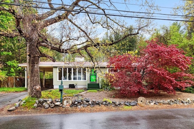 ranch-style home with fence, entry steps, a carport, and asphalt driveway