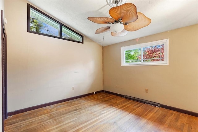 empty room with wood finished floors, vaulted ceiling, baseboards, and a ceiling fan