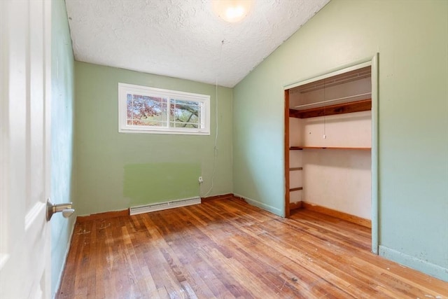 unfurnished bedroom featuring hardwood / wood-style flooring, a textured ceiling, baseboards, a closet, and vaulted ceiling