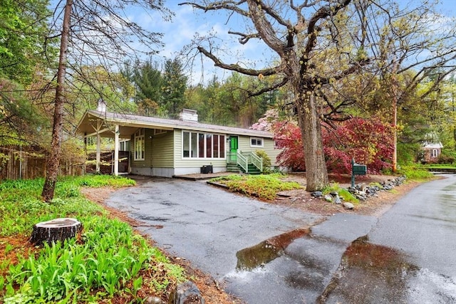 ranch-style home with driveway, fence, and a chimney