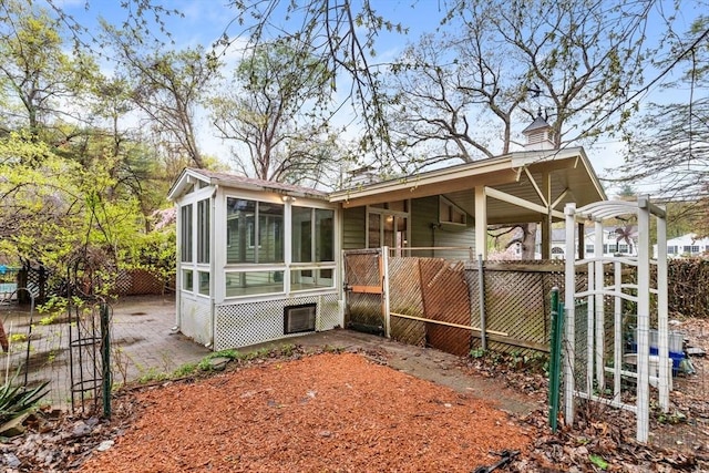 rear view of house featuring a sunroom and fence