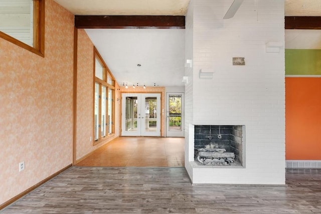 unfurnished living room with wood finished floors, french doors, a brick fireplace, baseboards, and ceiling fan