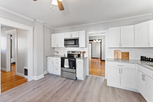 kitchen with appliances with stainless steel finishes, ceiling fan with notable chandelier, white cabinetry, light stone countertops, and light wood-type flooring