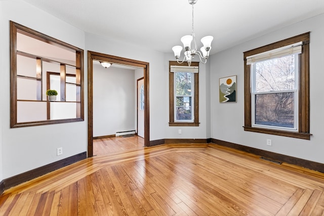 spare room with hardwood / wood-style flooring, a baseboard heating unit, and a chandelier