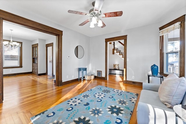 living room with hardwood / wood-style flooring, ceiling fan with notable chandelier, and a wealth of natural light