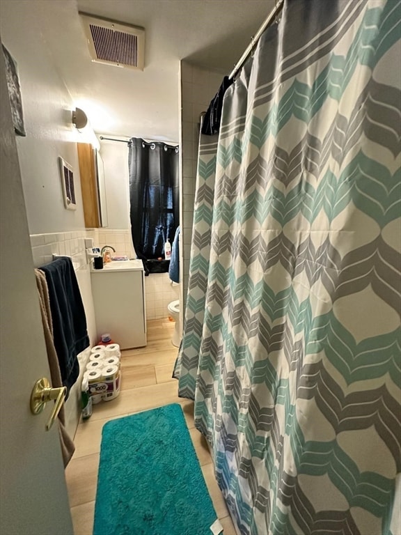 bathroom with walk in shower, toilet, vanity, tile walls, and hardwood / wood-style flooring