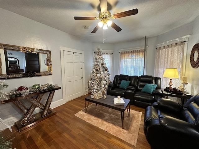 living room featuring dark hardwood / wood-style floors, ceiling fan, and a textured ceiling