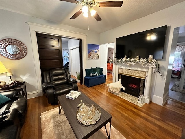 living room with hardwood / wood-style flooring, ceiling fan, a textured ceiling, and a high end fireplace