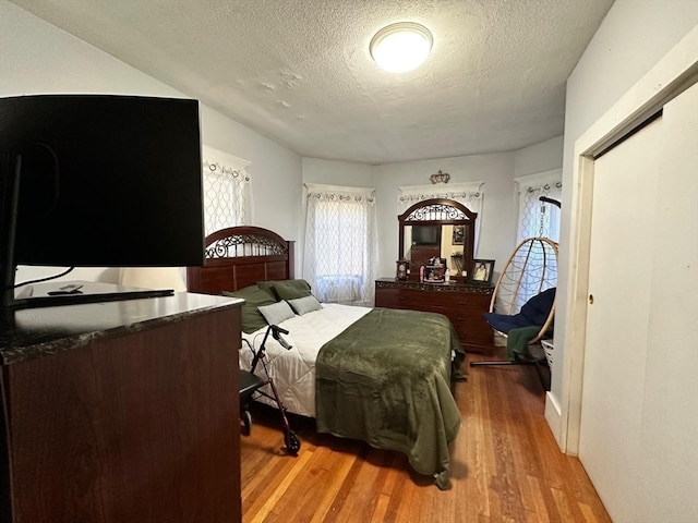 bedroom with a textured ceiling, hardwood / wood-style flooring, and a closet