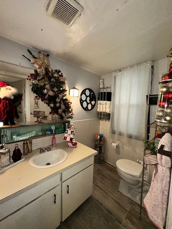 bathroom featuring vanity, toilet, and tile walls