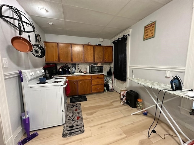 kitchen with decorative backsplash, sink, light wood-type flooring, and white electric range