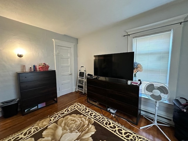 bedroom with dark wood-type flooring and a baseboard heating unit