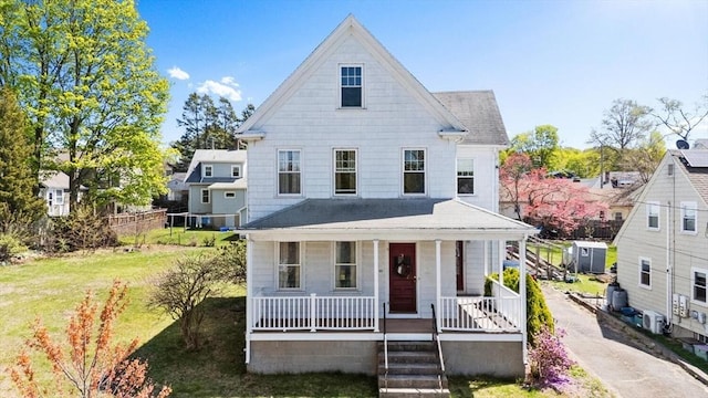 view of front of home with covered porch, a shingled roof, and a front lawn