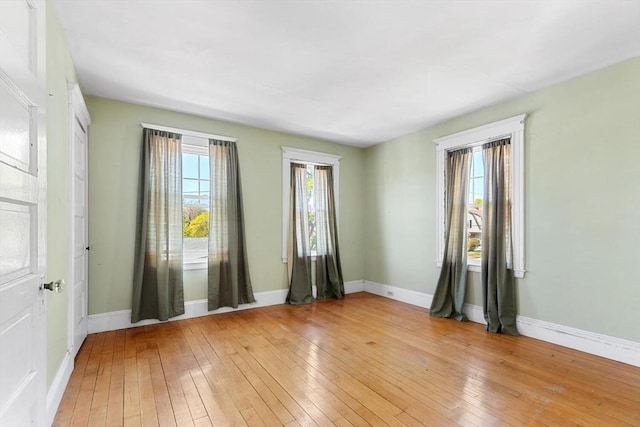 empty room with baseboards and light wood-type flooring