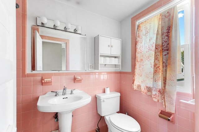 half bathroom featuring tile walls, a wainscoted wall, and toilet