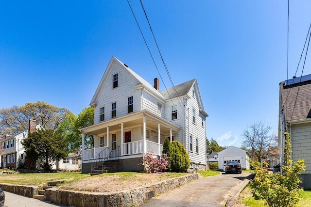 view of front of home with a detached garage, an outdoor structure, and a porch