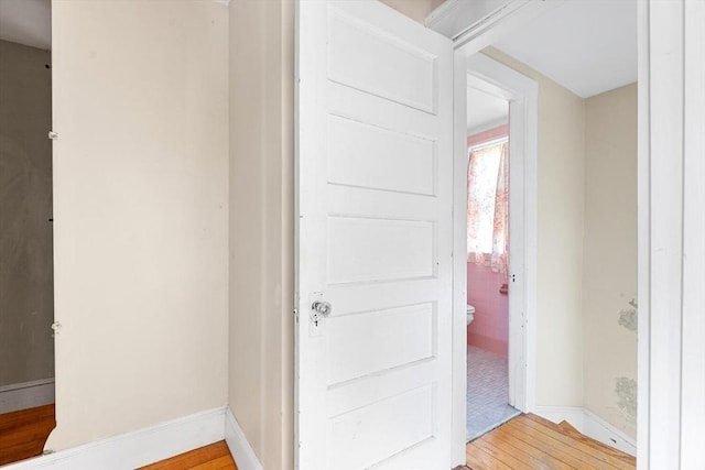 interior space with wood-type flooring, baseboards, and toilet