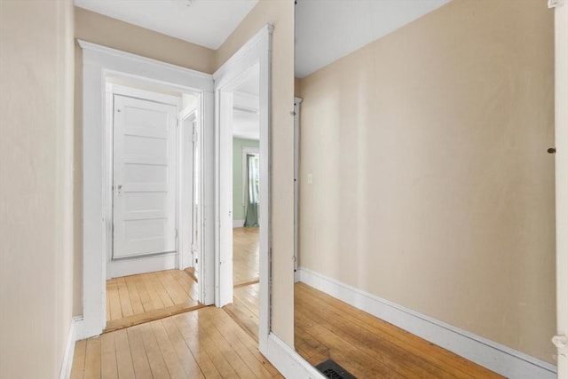 hall featuring baseboards and light wood-type flooring