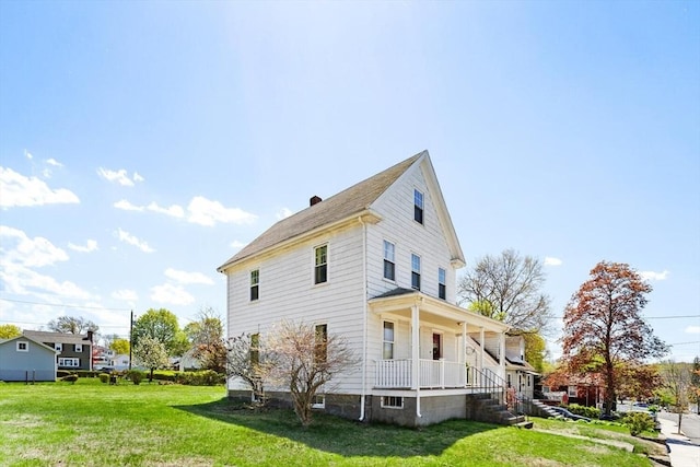 view of side of property featuring a yard, covered porch, and a chimney
