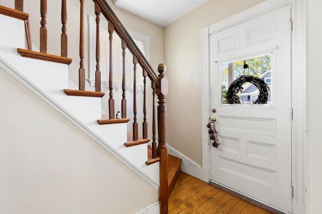 entryway featuring wood-type flooring, baseboards, and stairway