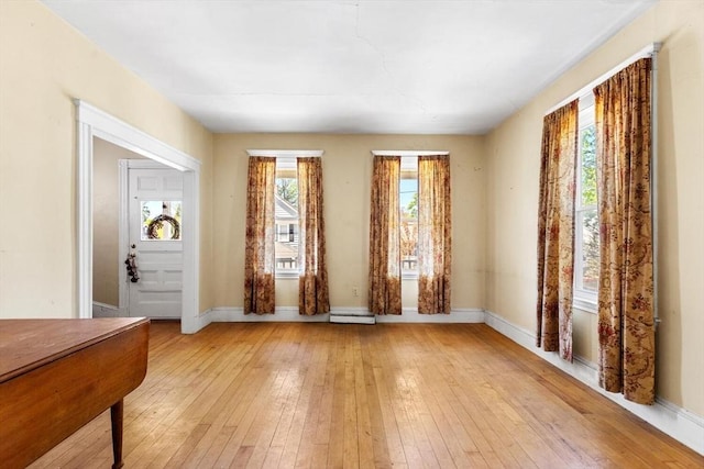 entrance foyer with baseboards, a baseboard radiator, and light wood-type flooring