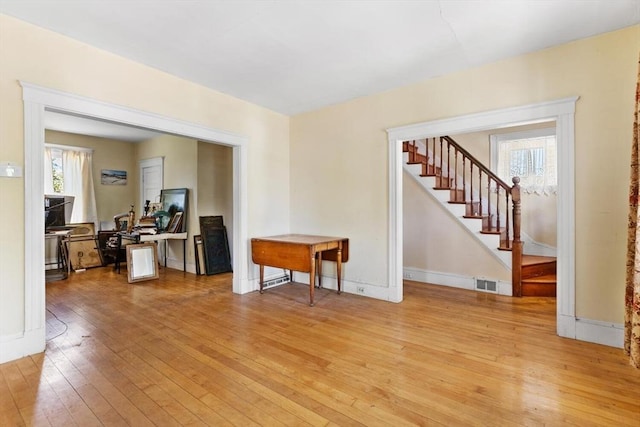 living room featuring stairs, visible vents, a wealth of natural light, and light wood-style flooring