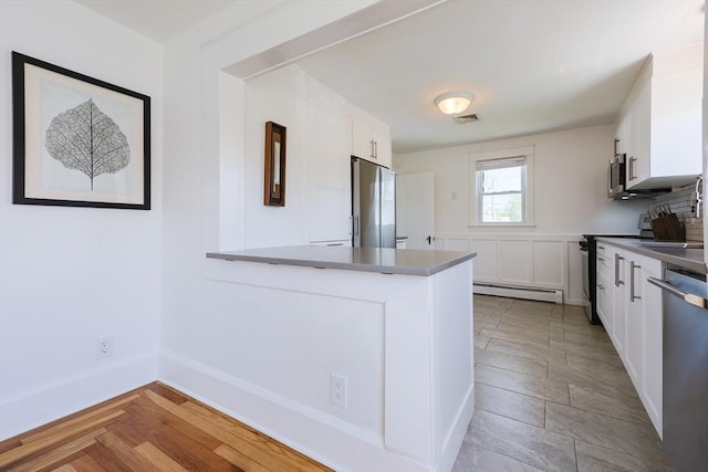 kitchen with stainless steel appliances, a baseboard radiator, white cabinetry, and a peninsula