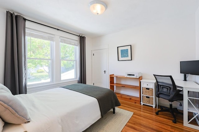 bedroom featuring wood finished floors and an office area