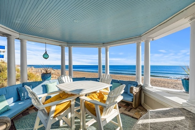 sunroom / solarium featuring a water view and a beach view