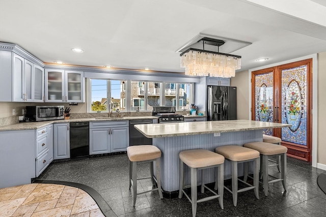 kitchen featuring a kitchen island, a breakfast bar, black appliances, sink, and decorative light fixtures