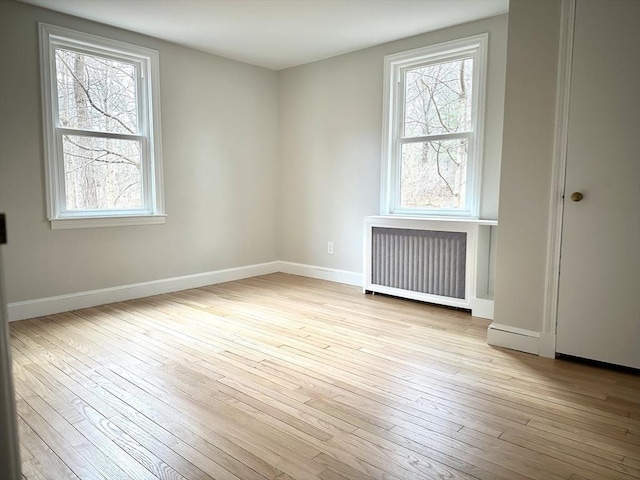 unfurnished room with hardwood / wood-style flooring, radiator heating unit, and baseboards