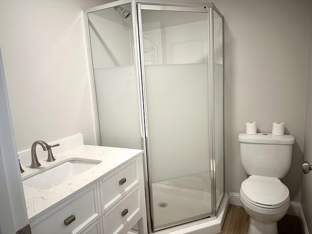 full bath featuring a stall shower, toilet, vanity, and wood finished floors