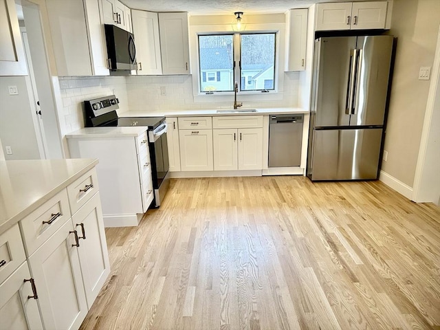 kitchen with a sink, light countertops, light wood-style floors, and stainless steel appliances