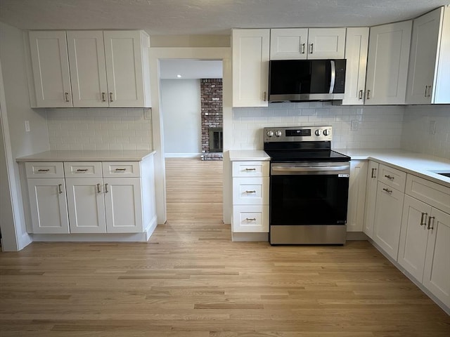 kitchen featuring light countertops, white cabinets, light wood-type flooring, and stainless steel appliances