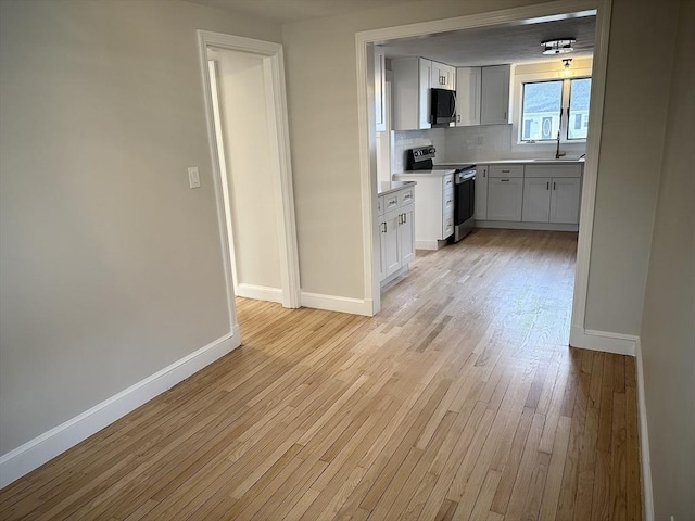 kitchen featuring a sink, stainless steel electric range oven, baseboards, and black microwave