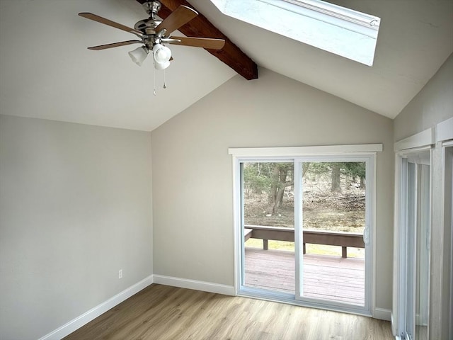 interior space featuring baseboards, vaulted ceiling with skylight, a ceiling fan, and light wood finished floors