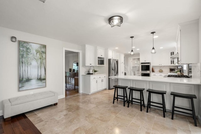 4 Country Way, Hopkinton, MA 01748 - kitchen with appliances with stainless steel finishes, a peninsula, white cabinets, light countertops, and a breakfast bar area