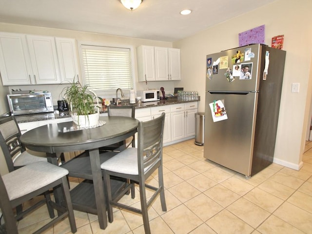 239 Union St, Franklin, MA 02038 - kitchen with freestanding refrigerator, white microwave, white cabinetry, light tile patterned floors, and dark countertops