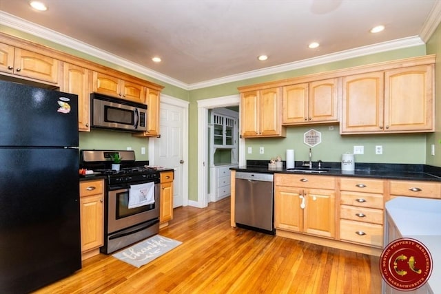 kitchen featuring a sink, stainless steel appliances, light wood-style flooring, and ornamental molding