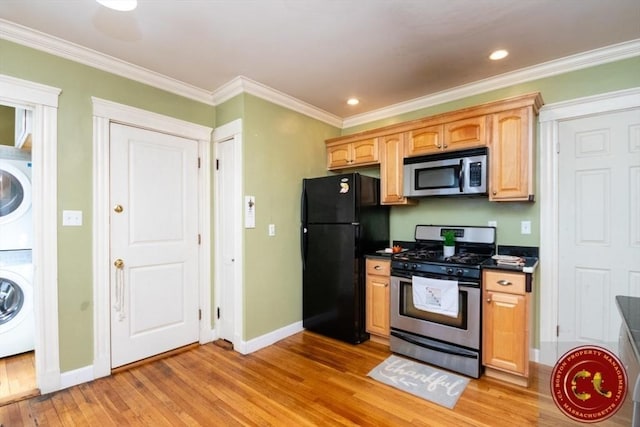 kitchen with dark countertops, stacked washer / dryer, crown molding, light wood-style floors, and stainless steel appliances