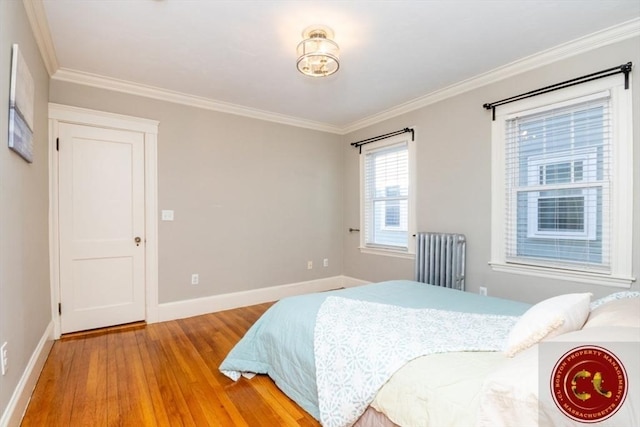 bedroom featuring baseboards, wood finished floors, radiator heating unit, and ornamental molding