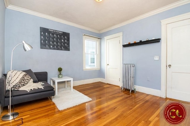 living area featuring baseboards, radiator, wood finished floors, and crown molding