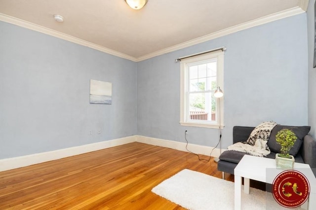 living area featuring crown molding, baseboards, and wood finished floors