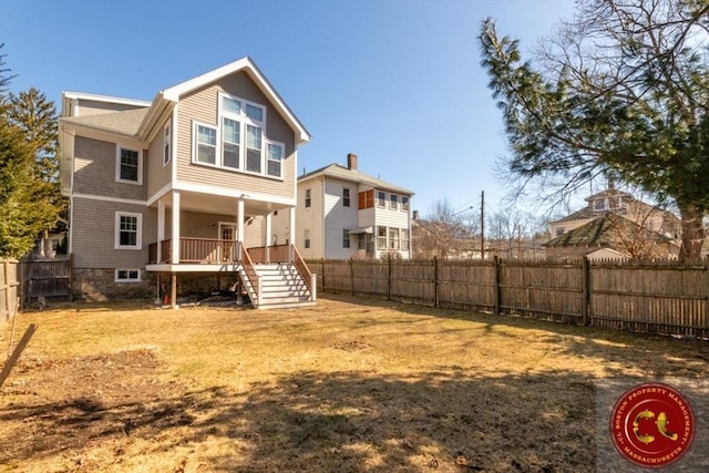 back of property with stairway, a yard, and fence