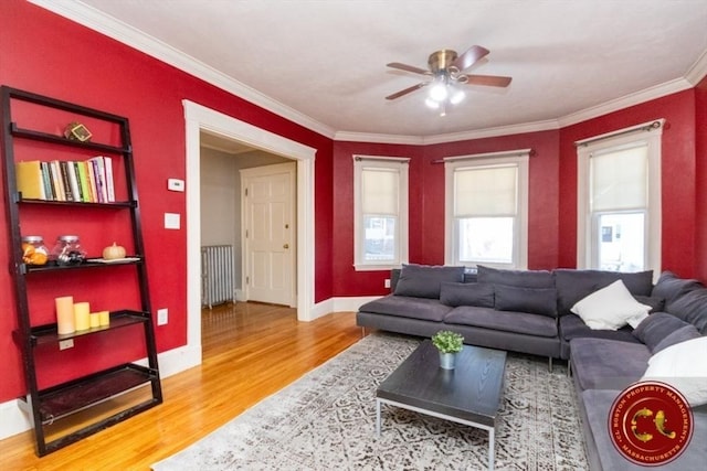 living room with baseboards, crown molding, a ceiling fan, and wood finished floors