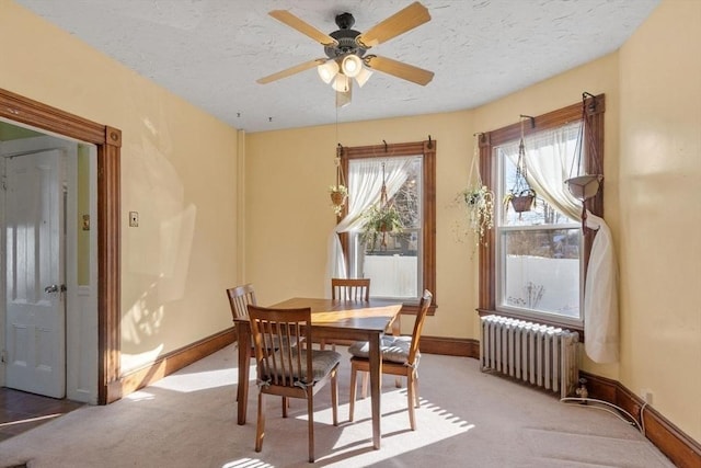 carpeted dining room with ceiling fan, radiator heating unit, and a textured ceiling