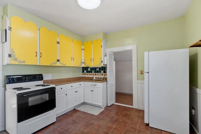 kitchen with white fridge, sink, electric range oven, and white cabinets