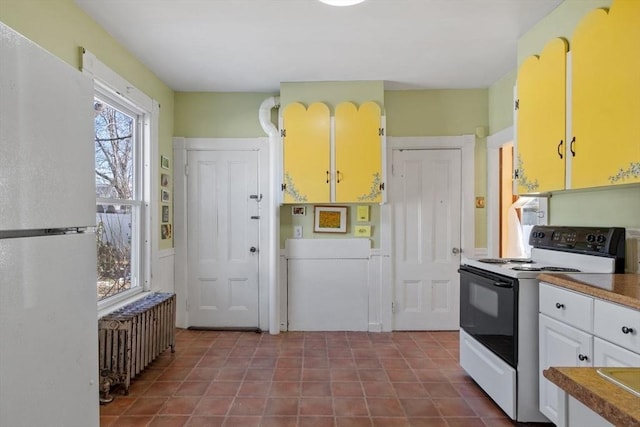 kitchen featuring range with electric cooktop, white fridge, radiator, and white cabinets